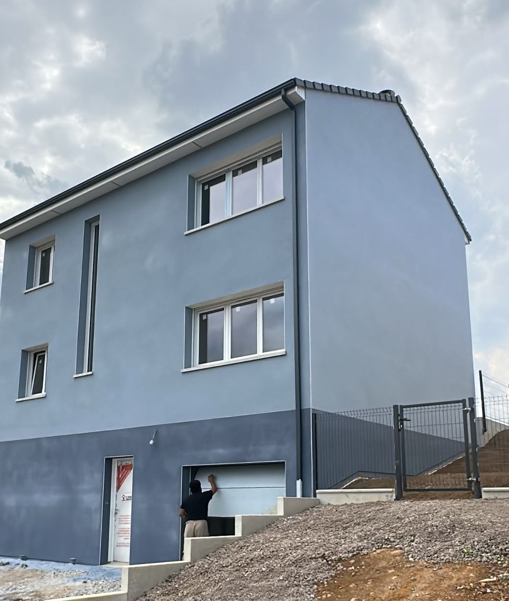 Gris-bleu, soubassement foncé : Maison neuve sur trois niveaux, enduit projeté gratté en deux teintes